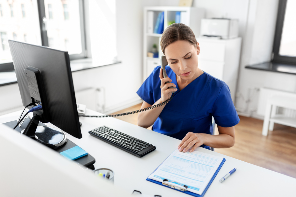 Doctor with Computer Calling on Phone at Hospital