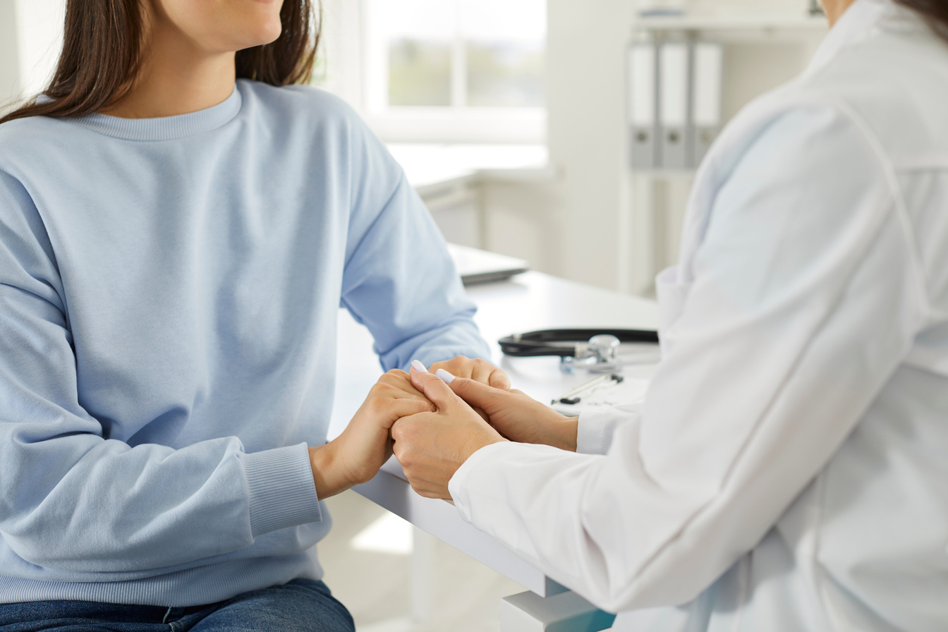 Female Doctor Holds Hand of Female Patient, Comforting Her, Expressing Sympathy and Support.